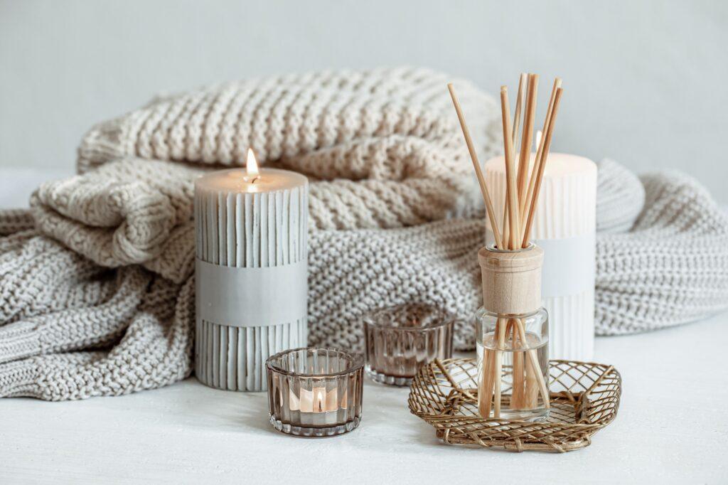 Cozy home composition with candles, aroma sticks and a knitted element.