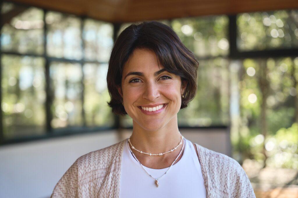 Young happy Hispanic woman holistic teacher looking at camera in yoga studio.